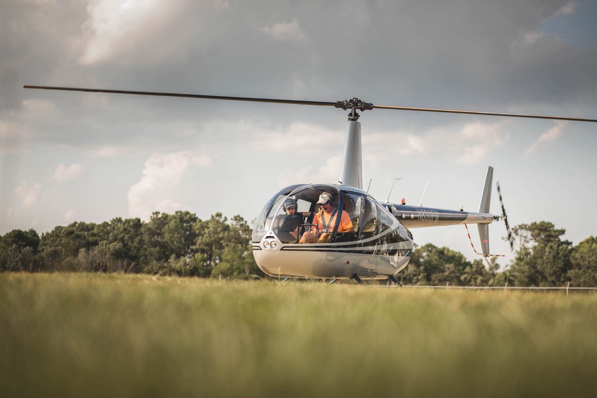 Helicopter parked on a lush green grassy field, surrounded by open space and clear skies.